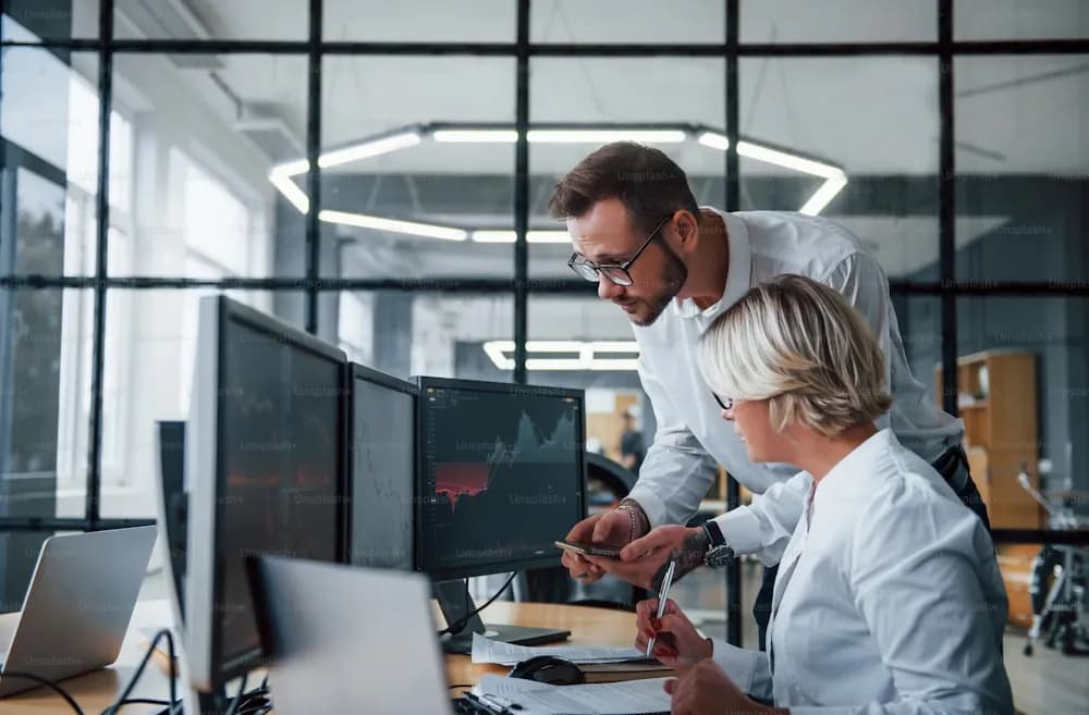 Two stockbrokers in formal attire analyzing financial information together in an office